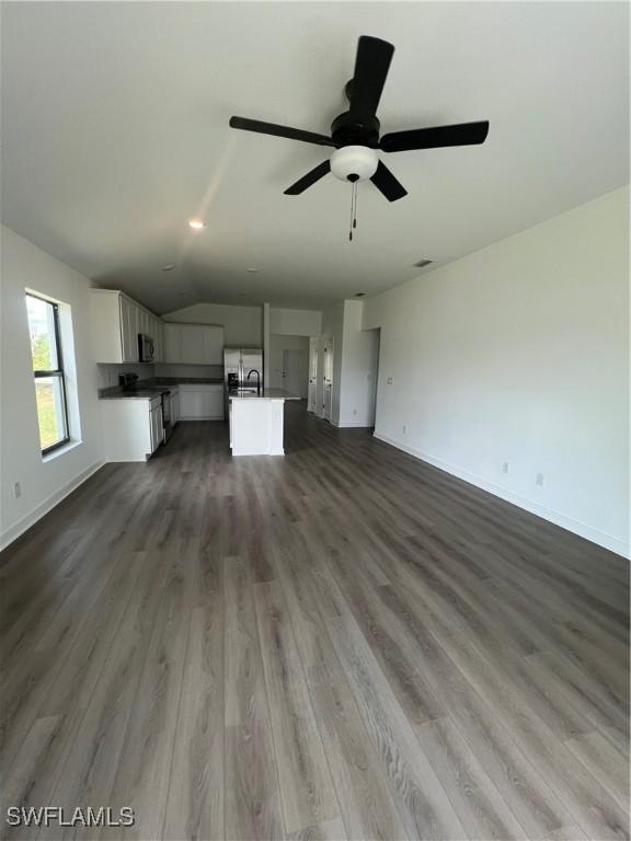 unfurnished living room featuring sink, vaulted ceiling, dark hardwood / wood-style floors, and ceiling fan