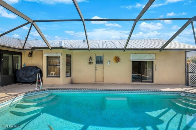 view of pool with glass enclosure, a patio area, and area for grilling