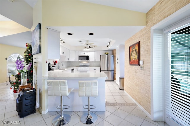 kitchen featuring sink, kitchen peninsula, light tile patterned floors, appliances with stainless steel finishes, and white cabinetry