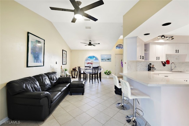 tiled living room with ceiling fan, sink, and vaulted ceiling