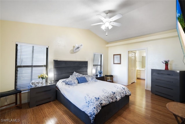 bedroom featuring ceiling fan, ensuite bathroom, lofted ceiling, and dark wood-type flooring