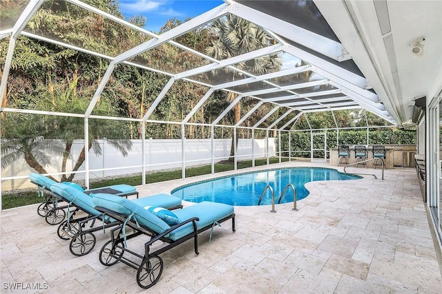 view of pool featuring glass enclosure, exterior kitchen, and a patio