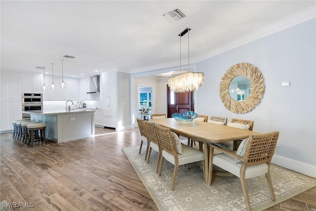 dining room featuring light wood-type flooring, ornamental molding, and a chandelier