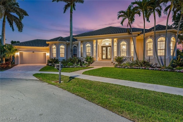 mediterranean / spanish home featuring a lawn, a garage, and french doors