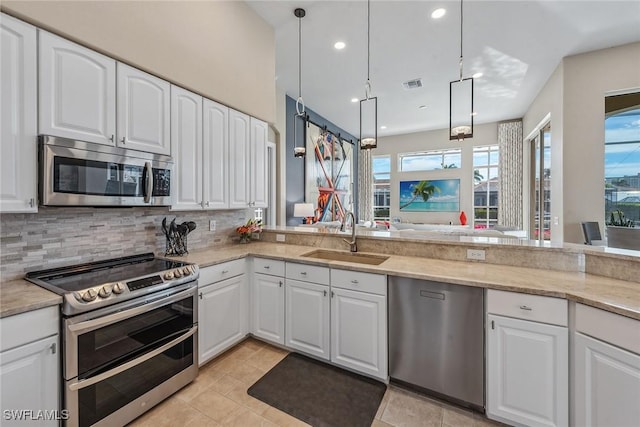 kitchen with hanging light fixtures, white cabinetry, sink, and stainless steel appliances