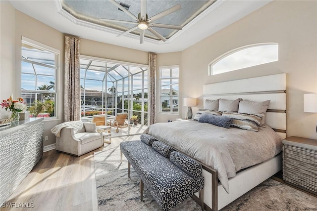 bedroom with ceiling fan, wood-type flooring, crown molding, and a tray ceiling