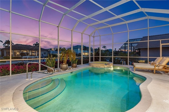 pool at dusk with glass enclosure and a patio area