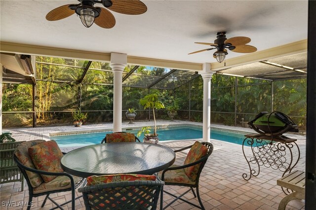 view of pool featuring glass enclosure, a patio area, and ceiling fan