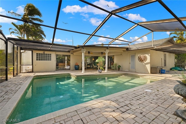 view of swimming pool with a patio, glass enclosure, and ceiling fan