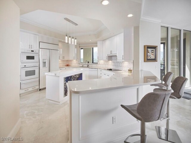 kitchen with a center island, white appliances, decorative light fixtures, a breakfast bar area, and white cabinets