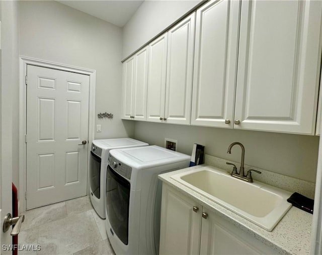 washroom with cabinets, independent washer and dryer, and sink