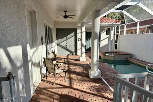 deck featuring glass enclosure, ceiling fan, a patio, and a pool with hot tub