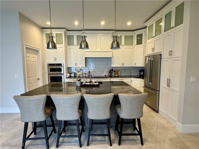 kitchen with pendant lighting, a kitchen island with sink, appliances with stainless steel finishes, and tasteful backsplash