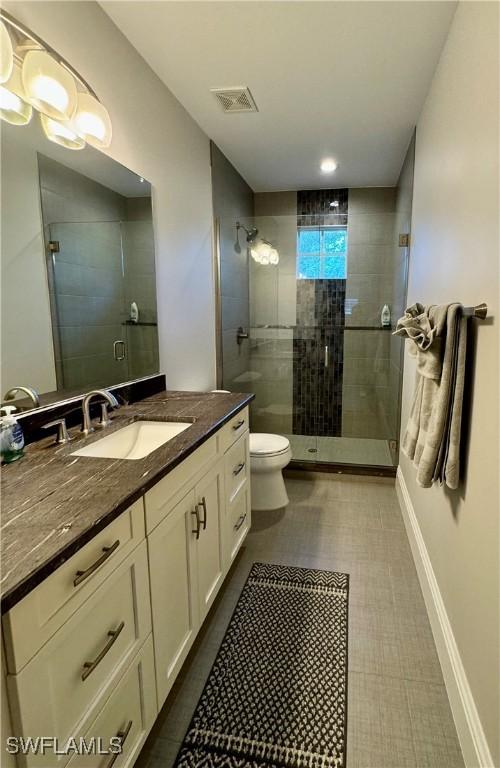 bathroom featuring vanity, toilet, and an enclosed shower