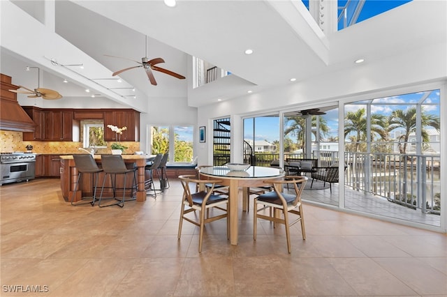 tiled dining room with a towering ceiling and a water view