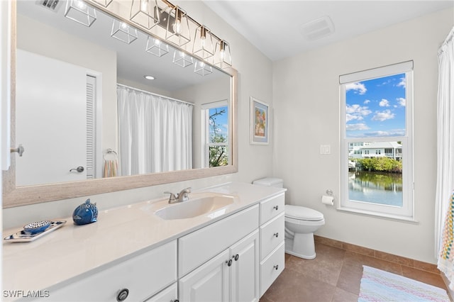 bathroom featuring tile patterned floors, vanity, toilet, and plenty of natural light