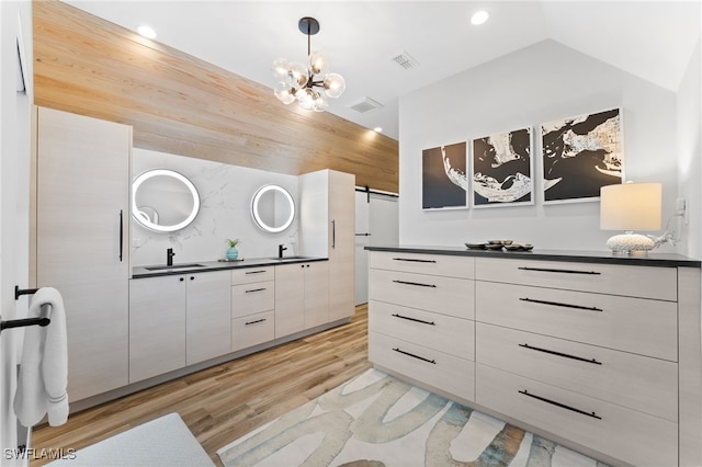 interior space with vaulted ceiling, an inviting chandelier, light hardwood / wood-style flooring, and sink