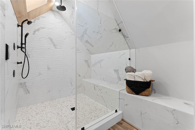 bathroom with a tile shower and lofted ceiling