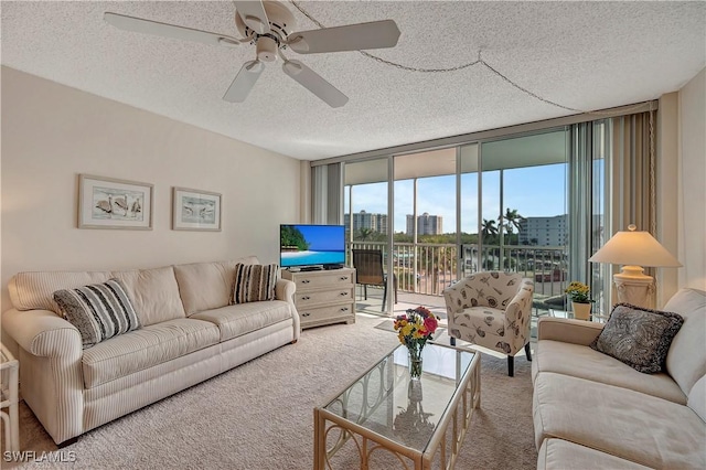 living room featuring ceiling fan, a wall of windows, carpet, and a textured ceiling