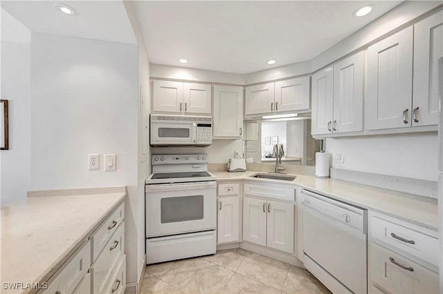 kitchen with white cabinetry, white appliances, sink, and light tile patterned floors