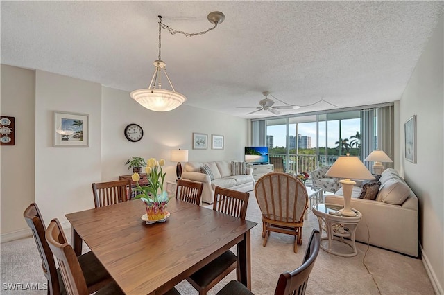 dining space with ceiling fan, a wall of windows, light carpet, and a textured ceiling