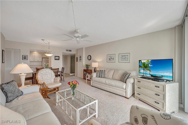 carpeted living room featuring ceiling fan and a textured ceiling