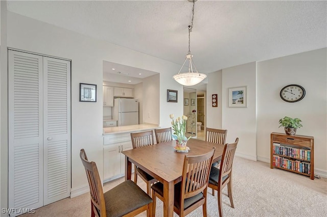 carpeted dining area with a textured ceiling