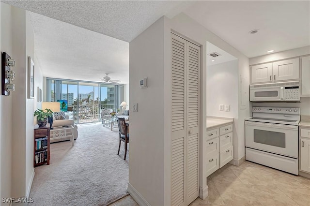 kitchen with expansive windows, white cabinetry, light carpet, and white appliances