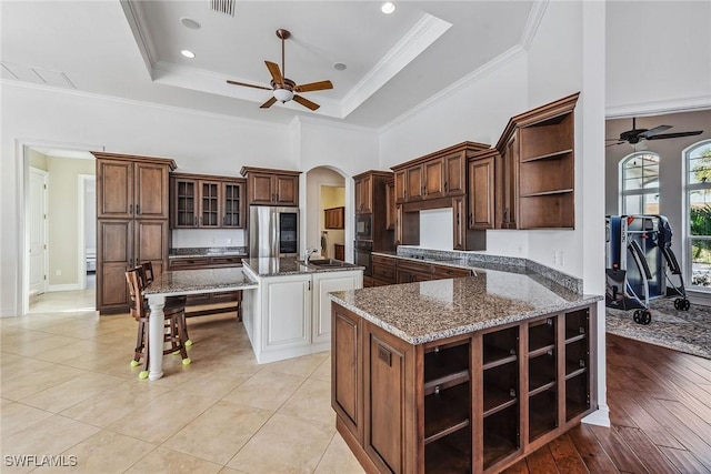 kitchen with a raised ceiling, stainless steel refrigerator, sink, and ornamental molding