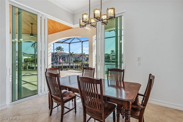 dining space with light tile patterned flooring, crown molding, and an inviting chandelier