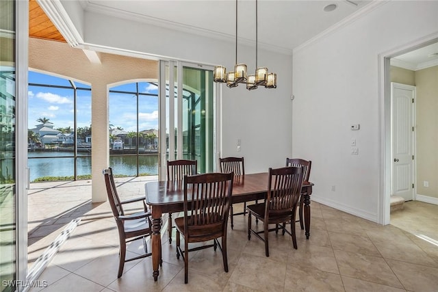 dining space with a water view, a chandelier, light tile patterned floors, and ornamental molding