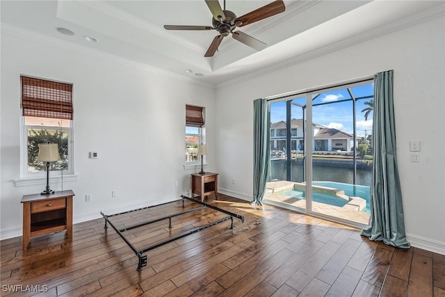 interior space with a tray ceiling, ceiling fan, a healthy amount of sunlight, and hardwood / wood-style flooring