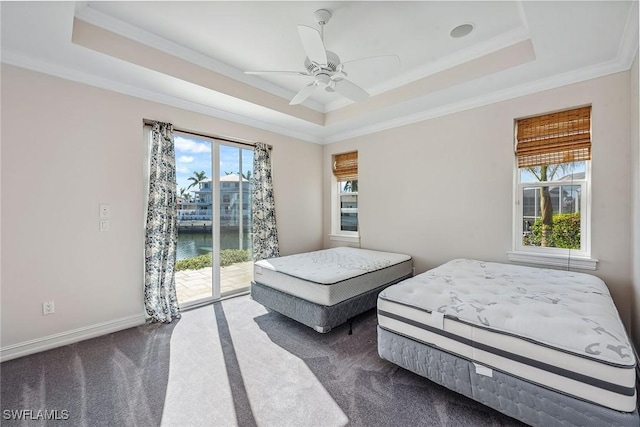 carpeted bedroom featuring access to exterior, a water view, a raised ceiling, and ceiling fan