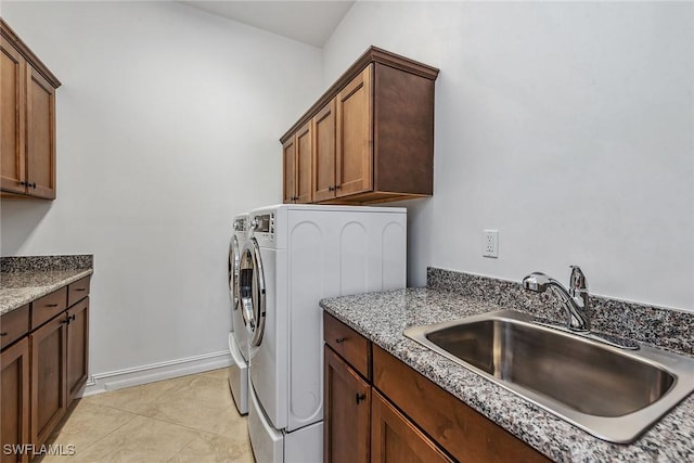 clothes washing area featuring cabinets, light tile patterned flooring, washer and dryer, and sink