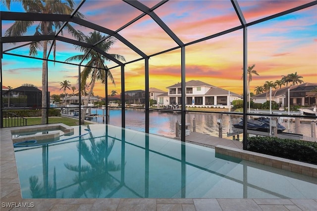 pool at dusk featuring glass enclosure, an in ground hot tub, a water view, and a boat dock