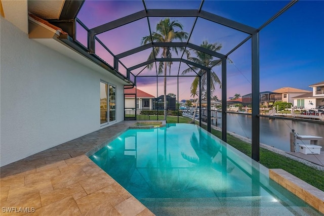 pool at dusk featuring a water view, glass enclosure, and a patio area