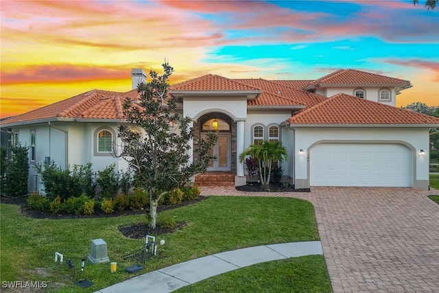 mediterranean / spanish home featuring a lawn and a garage