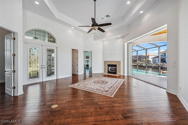 unfurnished living room featuring ceiling fan, dark hardwood / wood-style flooring, and a raised ceiling