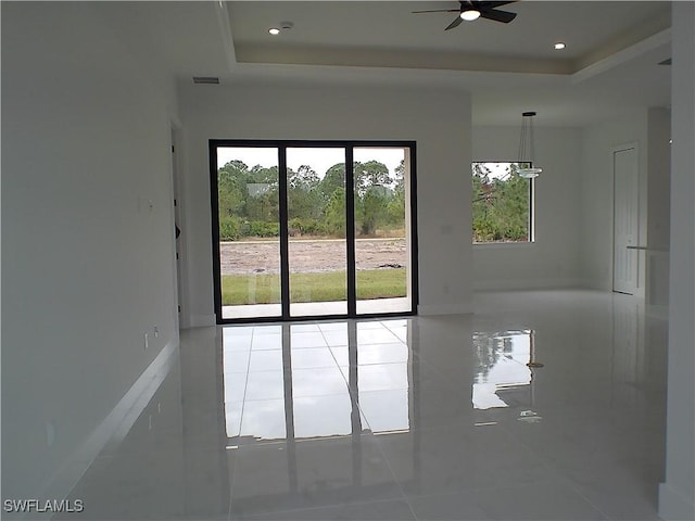 spare room with ceiling fan, tile patterned flooring, and a raised ceiling