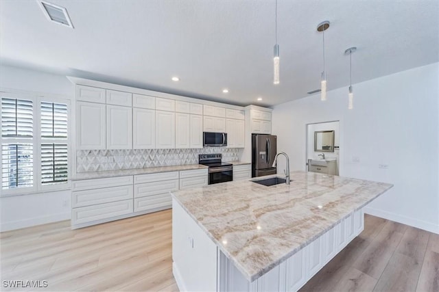 kitchen with white cabinets, appliances with stainless steel finishes, pendant lighting, and a spacious island