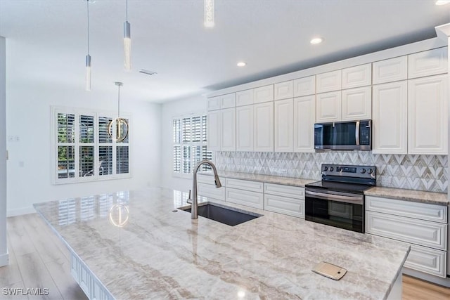 kitchen with appliances with stainless steel finishes, white cabinets, decorative light fixtures, backsplash, and sink