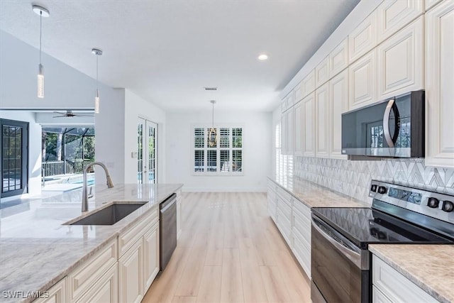 kitchen with light stone counters, decorative light fixtures, decorative backsplash, appliances with stainless steel finishes, and sink