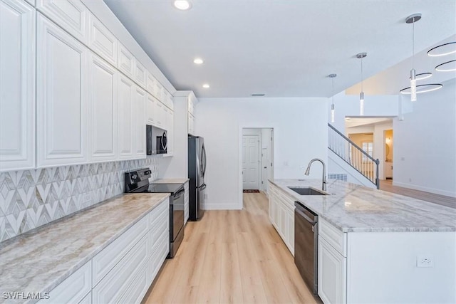 kitchen featuring stainless steel appliances, sink, white cabinetry, backsplash, and hanging light fixtures