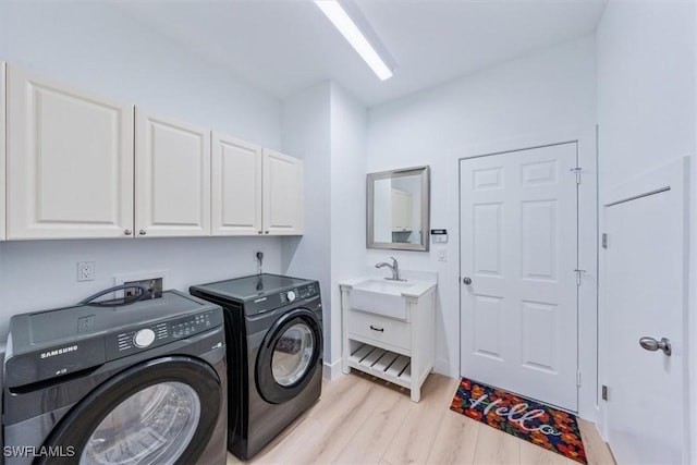 washroom featuring sink, cabinets, washer and clothes dryer, and light wood-type flooring