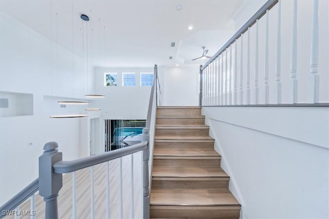 stairway featuring ceiling fan