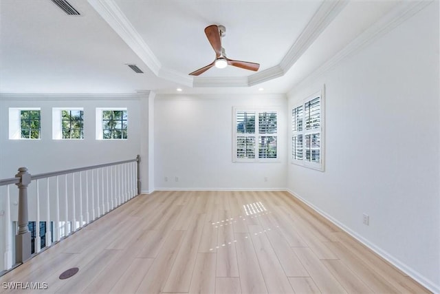 spare room featuring ornamental molding, light wood-type flooring, ceiling fan, and a tray ceiling