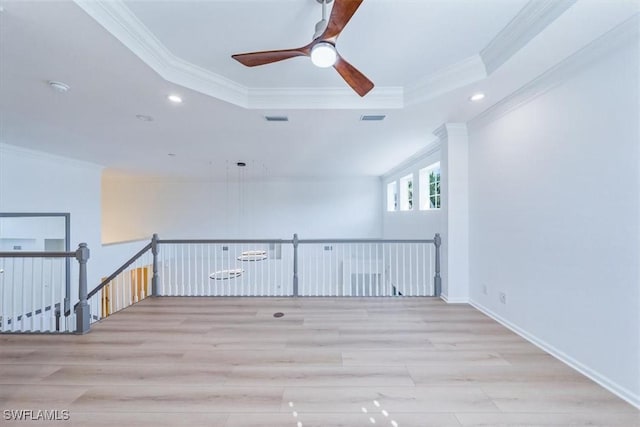 spare room featuring light wood-type flooring, a raised ceiling, and ornamental molding