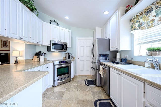 kitchen featuring stainless steel appliances, white cabinetry, and sink