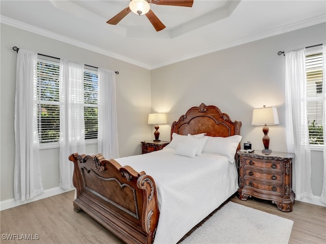 bedroom with crown molding, ceiling fan, a raised ceiling, and light hardwood / wood-style flooring