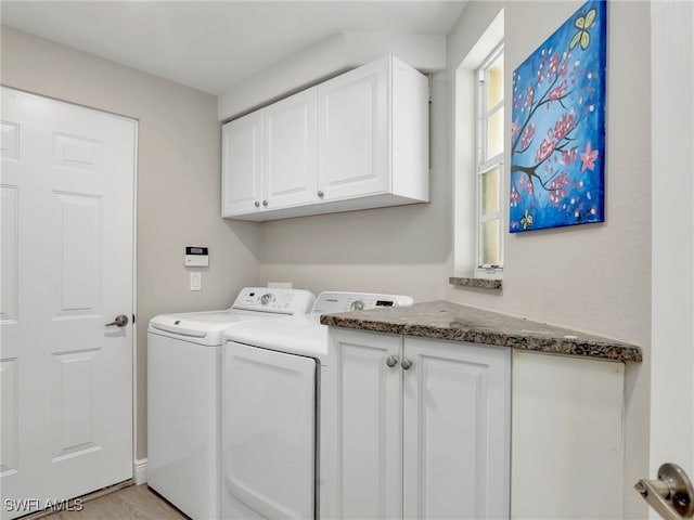 laundry room with cabinets, light wood-type flooring, and washer and clothes dryer